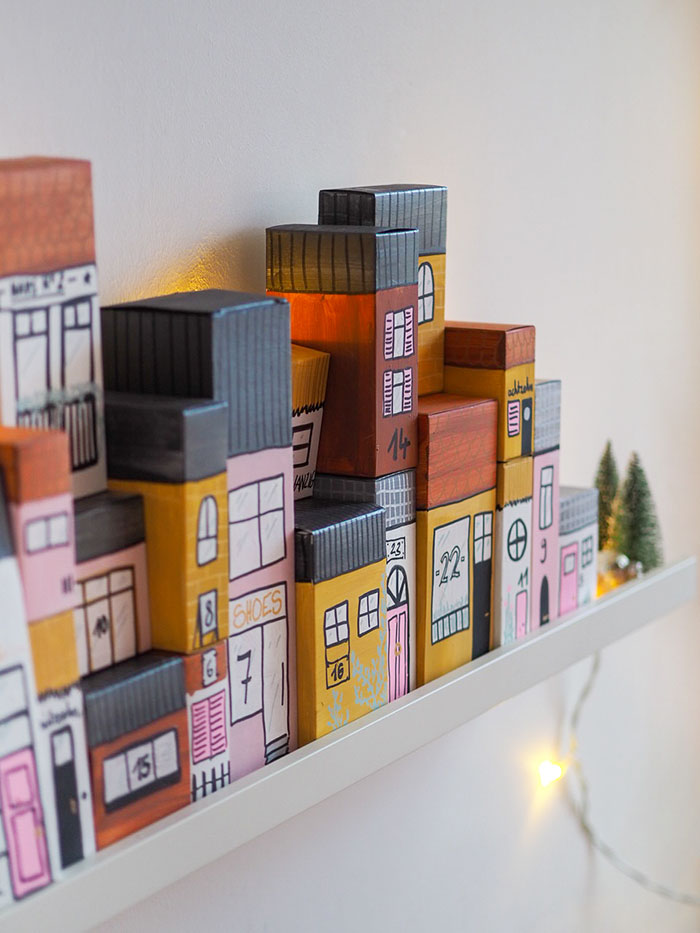 Aus Papp-Verpackungen (zum Beispiel von Lebensmitteln) kannst du mit ein bisschen Farbe und Fantasie einen tollen DIY Adventskalender basteln. Die upcycling Häuserzeile ist zudem noch eine tolle, weihnachtliche Dekoration.