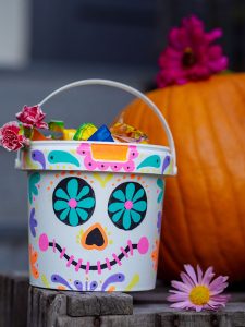Ein großer Joghurtbecher wird mit ein paar bunten Paintmarkern zu einem tollen DIY Süßigkeiten-Eimer für die Halloween-Beute. Ein kinderleichtes Upcycling-Projekt im Dia-de-los-Muertos Stil.